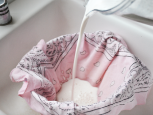 almond milk being poured through cloth to strain nut milk